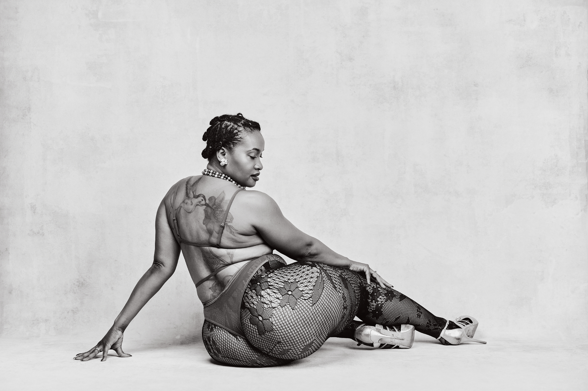 Black-and-white seated boudoir portrait in fishnet styling